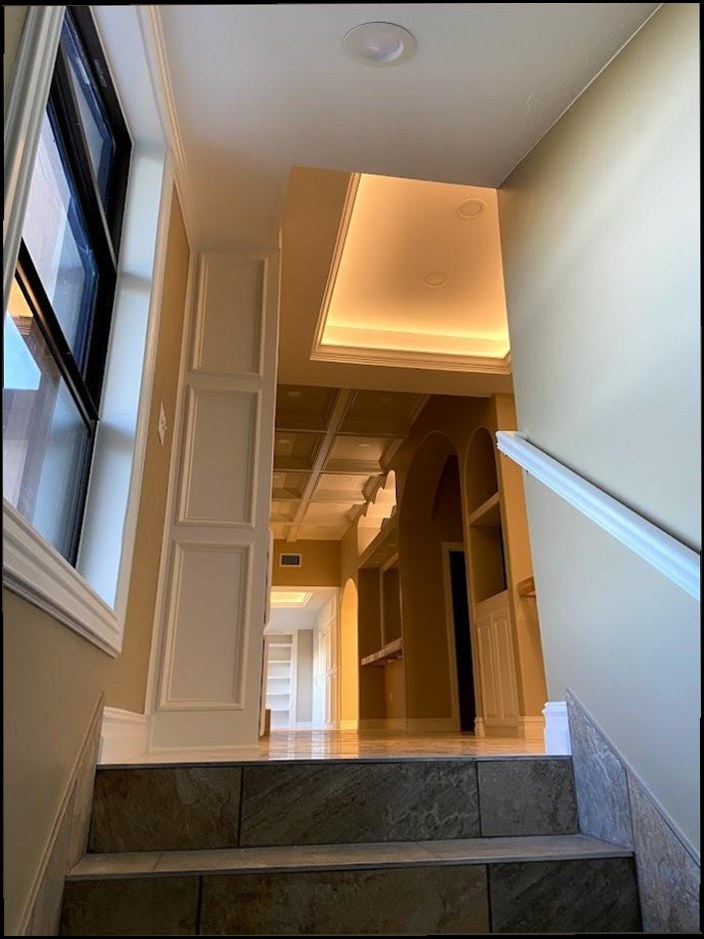 Hallway and stairwell with recessed downlights and a lit ceiling recess